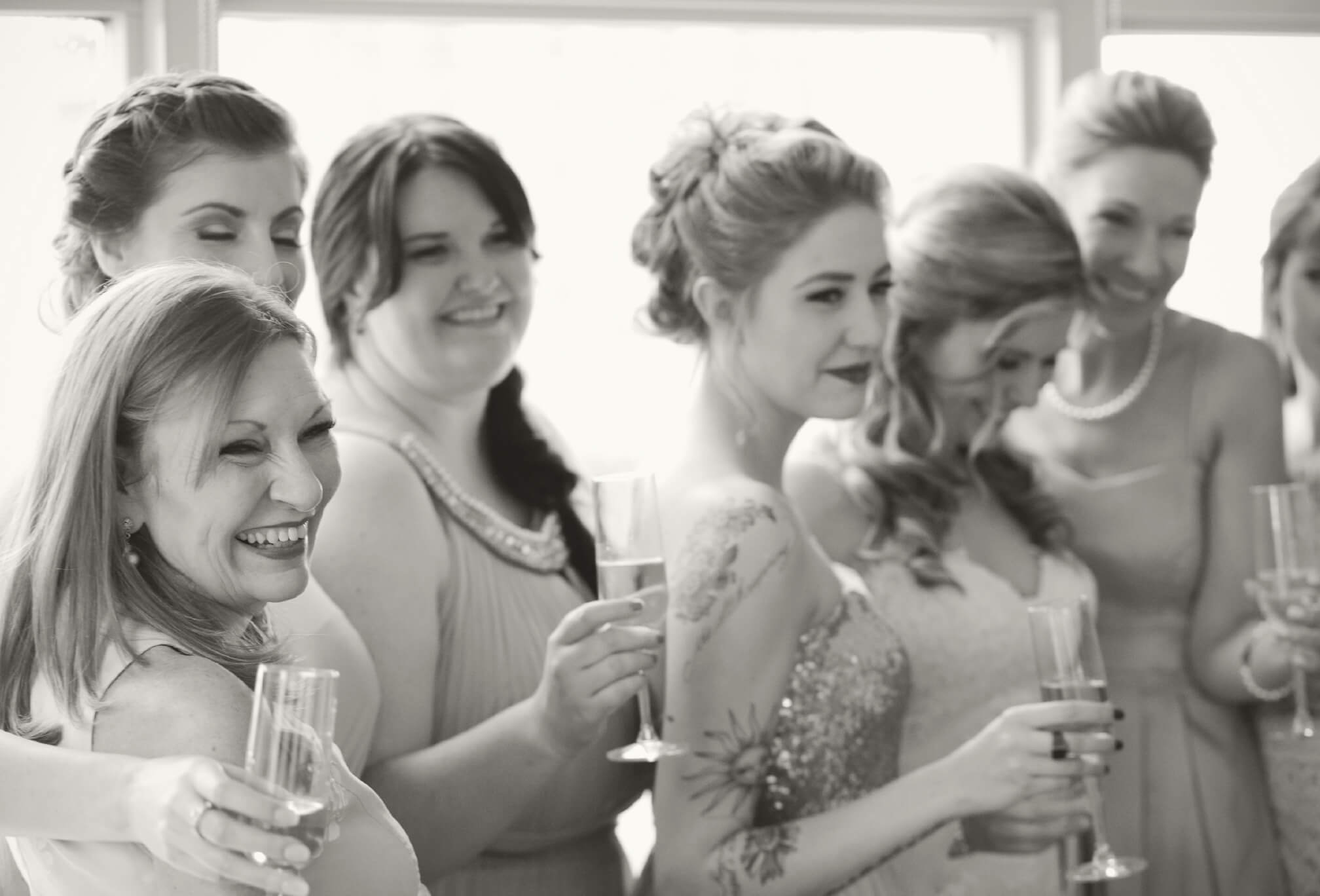 bride and bridesmaids champagne toast laugh